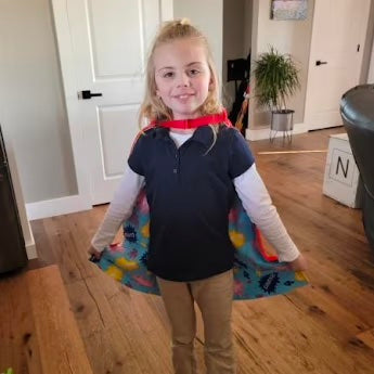 Girl standing showing off her red TinySuperheroes Cape